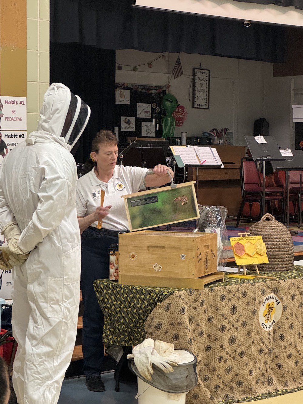 SBA member showing educational items to volunteer in a bee suit
